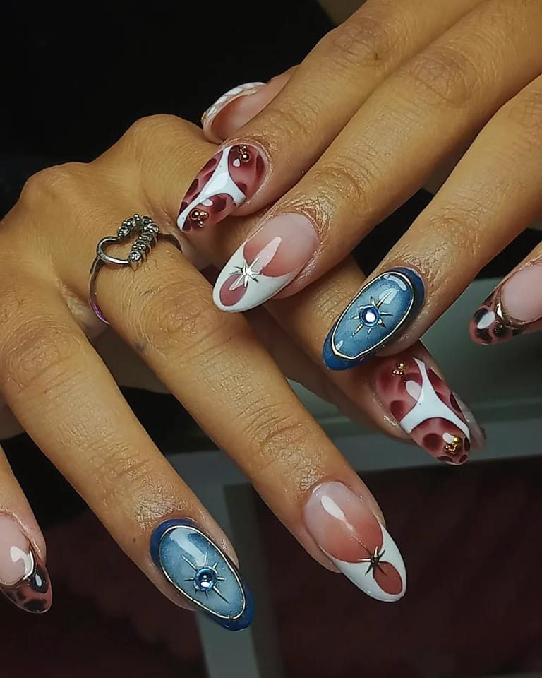 Uñas almendra con espirales rojas y un ojo decorativo en azul