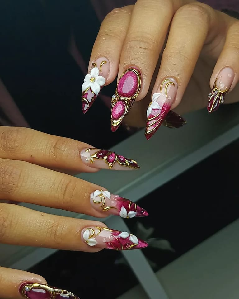 Uñas almendra largas con arte floral ornamentado en rojo y dorado